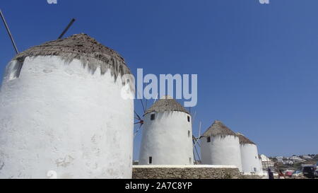 Mykonos, Grèce : célèbre moulins de Mykonos island lors d'un coucher du soleil après une journée ensoleillée d'été le long de la mer bleue Banque D'Images