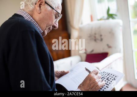 Man Doing Crossword Puzzle à la maison Banque D'Images