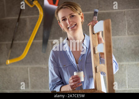 Portrait de femme mature à l'atelier de meubles Upcycling Accueil Peinture chaise en bois Banque D'Images