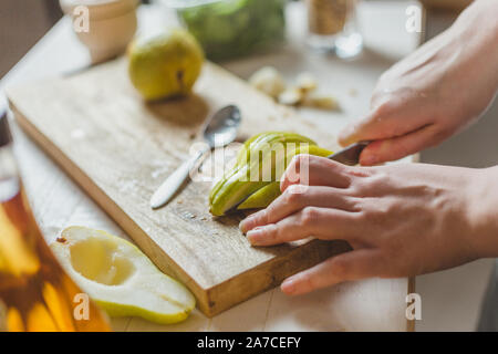 Découper les poires en salade sur une planche en bois faits maison - Recette - mains de la ménagère - rural Banque D'Images