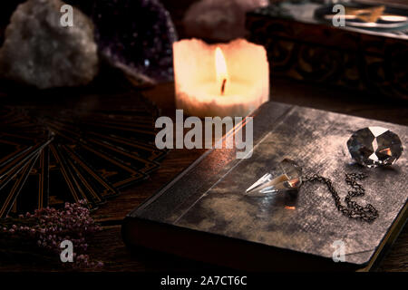 Nature morte à la bougie allumée sur la table en bois noir, carte de guichet de fortune, livre de magie et cristal et boîte pentagramme pendule. Convient pour mag Banque D'Images