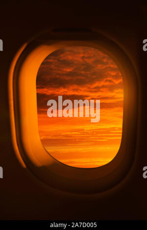 Afficher la fenêtre d'un avion d'un coucher de soleil rouge vif Banque D'Images
