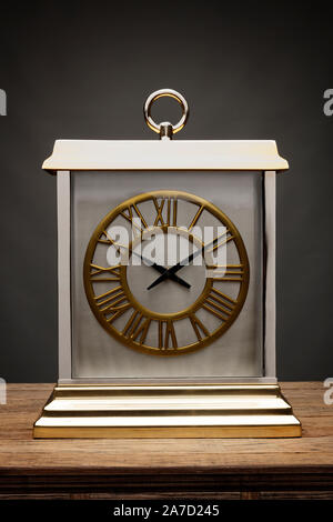 Un luxe chariot d'or et d'argent, horloge tourné sur une table en bois, avec un fond gris foncé Banque D'Images