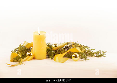 Copie de Noël l'espace avec une bougie allumé en jaune, des branches de pins, ruban de satin doré couleur or et des boules de Noël sur un fond à motifs Banque D'Images