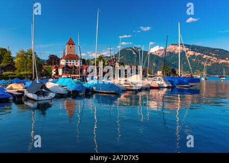 Église et Château de Spiez au bord du lac de Thoune avec yachts dans le canton suisse de Berne au coucher du soleil, Spiez, Suisse. Banque D'Images