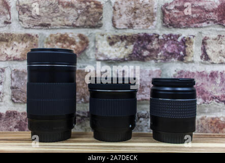 Divers Les objectifs d'appareil photo sur une table en bois avec un fond de brique rouge Banque D'Images