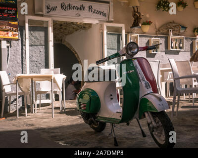 Moto Vespa en couleurs de drapeau italien en face de restaurant traditionnel et pizzeria avec lettrage à Tropea, Calabre, Italie Banque D'Images