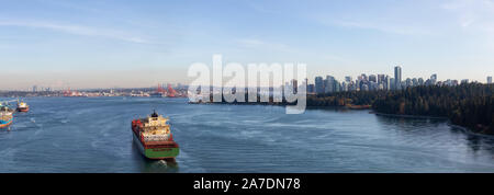 Vancouver, Colombie-Britannique, Canada. Vue panoramique à partir de l'antenne au-dessus d'un cargo arrivant au port avec le centre-ville de ville en arrière-plan en Banque D'Images