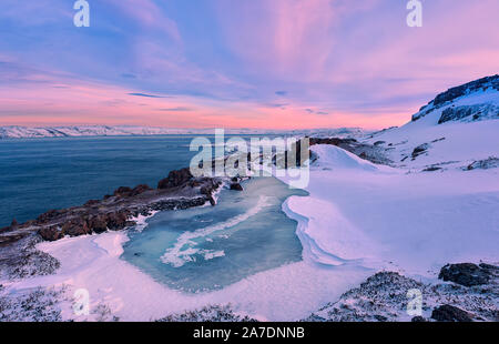 Un petit lac gelé et le littoral de la mer de Barents au coucher du soleil. Teriberka, région de Mourmansk, péninsule de Kola. La Russie. L'accent principal sur le lac gelé. Banque D'Images