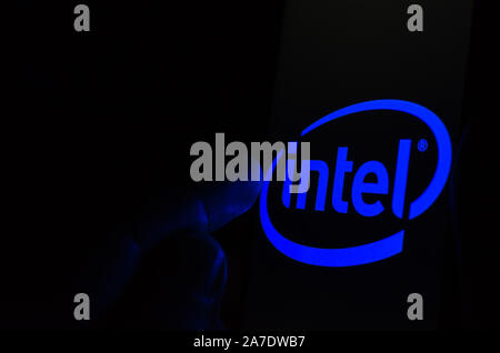Logo Intel sur un smartphone écran dans une pièce sombre et un doigt de le toucher. Banque D'Images