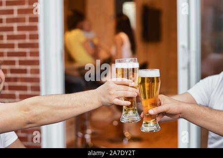 Image recadrée mains d'un groupe de fait part de verres de bière, des partis et des célébrations. verres à la maison sur la terrasse de la maison, la famille d'un Banque D'Images