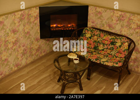 Tasse de café canapé et cheminée. Salon de détente à la maison ou dans un hôtel. Un agréable lieu de repos près de la cheminée. Table basse en verre et tasse blanc w Banque D'Images