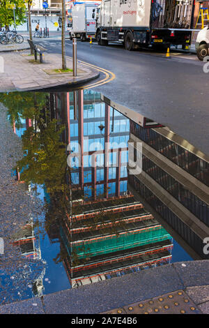 Partie du Cercle Square (en construction, Oct 2019), ce qui se reflète dans une flaque, Chester Street, près d'Oxford Road, Manchester, England, UK Banque D'Images