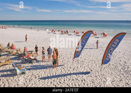 Les gens sur la plage de sable blanc à côté d'un bar de plage utilisant des bannières pour annoncer la nourriture et les boissons au restaurant Pompano Joe's iMiramar Beach Florida, USA. Banque D'Images