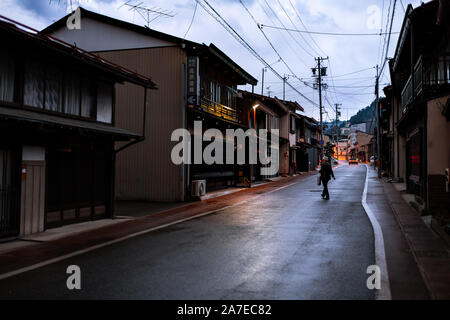 Takayama, Japon - 8 Avril 2019 : Ville de Gifu dans village traditionnel de nuit avec lampes lanterne illuminée et la femme crossing street road Banque D'Images