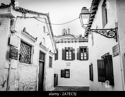 Kos Grèce - 31 juillet 2019 ; Ruelle entouré de bâtiments de l'île typiquement grec avec des volets et des fenêtres et des lampes avec tour de l'église à dista Banque D'Images