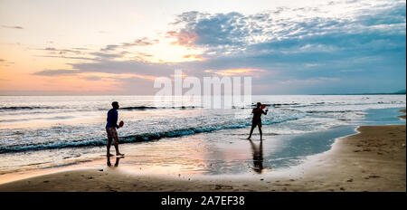 Un couple homosexuel jouer de la pagaie dans la plage sur un beau coucher de soleil Banque D'Images