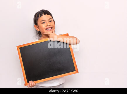 Enfant tenant conseil vide noir avec drôle loi. Concept Retour à l'école. Mur arrière-plan. Débardeur blanc. En regardant la caméra. Banque D'Images