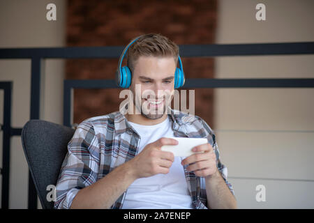 Cheerful businessman ayant reste tout en jouant le jeu sur le téléphone Banque D'Images