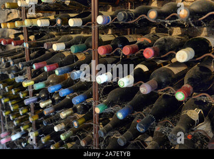 Des bouteilles de vin poussiéreux dans une cave à vin. Les bouteilles de vin empilées dans ancienne cave à vin close-up arrière-plan. Caves souterraines Banque D'Images