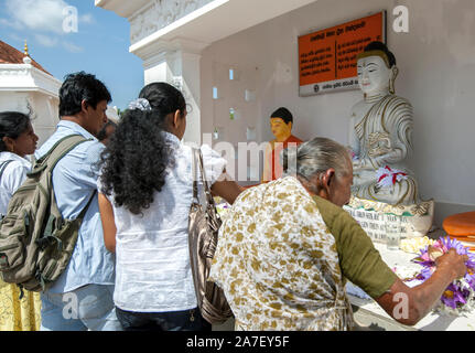 Pèlerins bouddhistes à Anuradhapura au Sri Lanka place des fleurs de lotus à un temple contenant des statues de Bouddha assis à côté de l'Ruwanwelisiya Dagoba. Banque D'Images