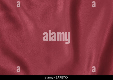 Arrière-plan de couleur rouge foncé de tissu drapé doux. Belle Soie satin tissu texturé pour la confection des vêtements et des rideaux. Texture textile élégant. Banque D'Images