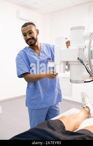 Young smiling doctor en uniforme bleu à l'aide de nouveaux équipements médicaux Banque D'Images