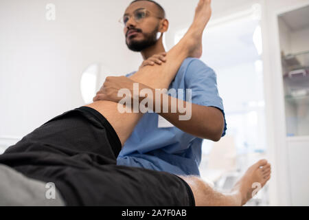 Le massage professionnel médical qualifié de genou malade patient in hospital Banque D'Images