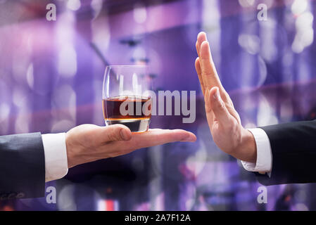 Close-up of Businessman part rejetant verre de Whisky offert par l'entrepreneur contre l'arrière-plan lumineux Banque D'Images