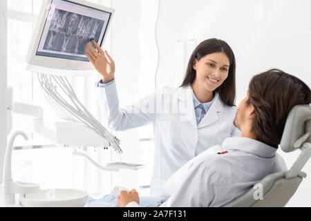 Belle femme médecin dentiste montrant son patient les résultats radiologiques Banque D'Images