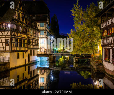 Vue de nuit sur un pont dans le quartier de la Petite France à Strasbourg, en France, sur le canal bordé de maisons à colombages se reflétant dans l'eau. Banque D'Images