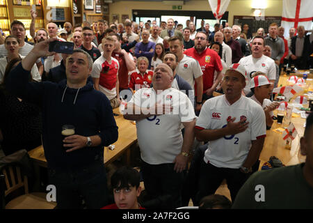 Angleterre fans observer l'hymne national avant la finale de la Coupe du Monde de Rugby l'affichage à l'ancienne, le RFC Albanais Woollam les terrains de jeu, St Albans. Banque D'Images