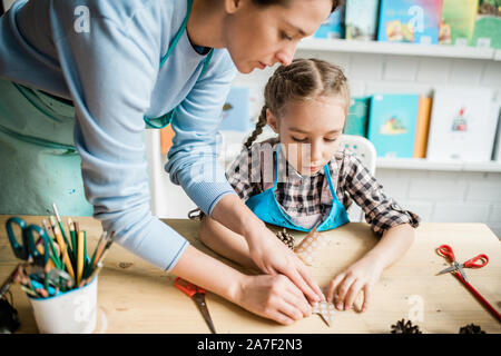 Jeune enseignant aider fille mignonne avec des décorations pour holiday at lesson Banque D'Images