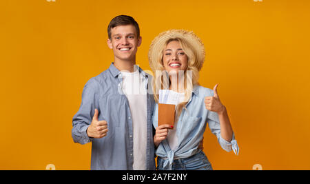 Cheerful couple de nationalités avec les billets et showing Thumbs up Banque D'Images