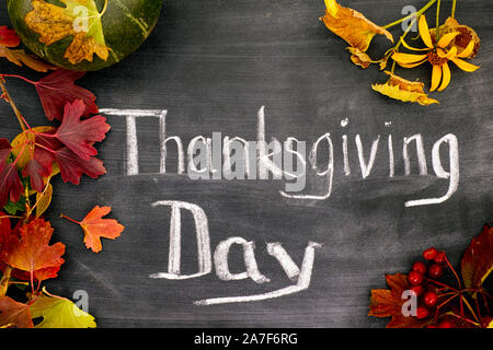 Mots jour de Thanksgiving écrit sur tableau noir à la citrouille et les feuilles d'automne. Close-up Banque D'Images