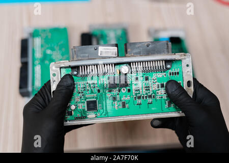 Les mains gantées de réparateur professionnel détenant une partie de gadget démontés Banque D'Images