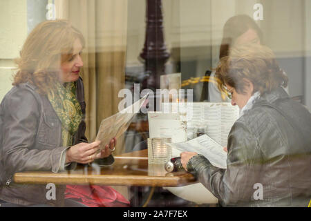 Deux femmes lecture des menus dans cafe à Amsterdam. Vue de côté. Plan moyen. Banque D'Images