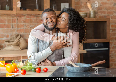 Portrait de jolie black couple embracing at kitchen Banque D'Images