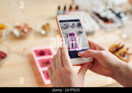 Mains de girl with smartphone taking photo of handmade soap dans les moules en silicone Banque D'Images