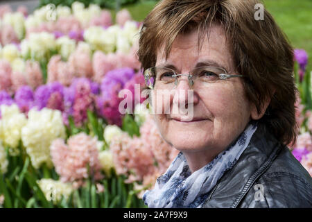 Portrait de femme d'âge moyen au jardin botanique avec les jacinthes arrière-plan. L'accent sur le premier plan. Banque D'Images