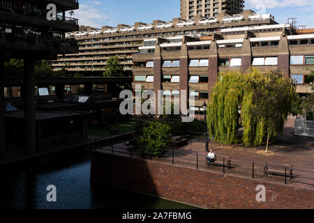 Un homme lit un livre en été au Barbican Centre à Londres, Royaume-Uni Banque D'Images