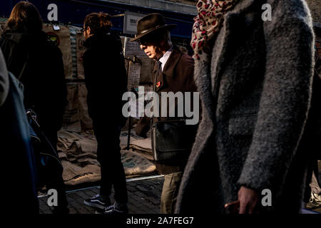 Un homme âgé attrape la lumière du soleil reflétée sur Sclater Street à Bethnal Green, Londres Est Banque D'Images