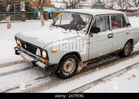 Une vieille Lada russe fait son chemin le long d'une route enneigée. Image prise dans le pays non reconnus de la Transnistrie, également connu sous le nom de Pridnestrovie Banque D'Images