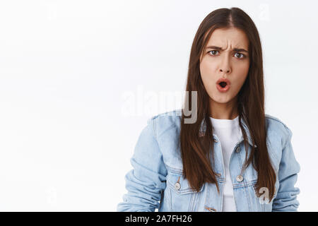 Choqué et surpris sans voix jeune femme en veste en denim, stare frustrés dire wtf, c'est que, d'un halètement surpris en fronçant les lèvres que voir quelque chose Banque D'Images