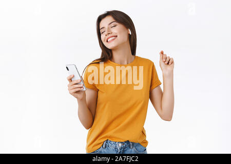 Moderne et élégant d'offres sans souci en jaune femme T-shirt bénéficiant d'awesome battent à nouveau les écouteurs sans fil, la danse avec les mains et pose détendue Banque D'Images