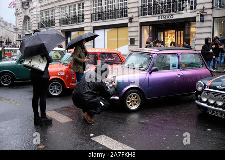 Westminster, England, UK. 2 novembre 2019.Le Regent Street Motor Show, un événement qui met en vedette 125 ans de l'automobile véhicule qui a eu lieu aujourd'hui sur l'image. L'événement disposent d'un grand nombre de véhicules et participant de la course de voiture à Bonham se tiendra demain à partir de Londres. Visiteurs bravant la pluie inspection vintage Austin mini voiture. Credit : JF Pelletier/Alamy Live News. Banque D'Images