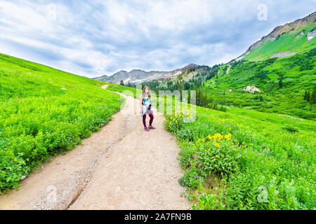 Albion, bassin d'été de l'Utah avec grand angle de femme debout sur route raide vue paysage de montagnes Wasatch dans sentier des fleurs sauvages Banque D'Images