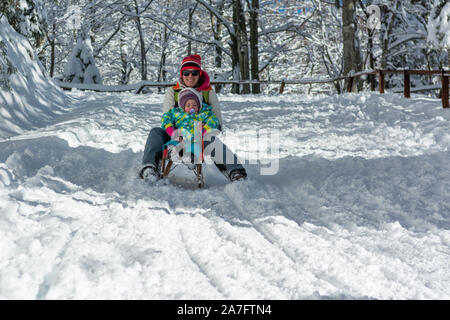 Mère et fille l'accélération en descente sur traîneau en bois. Banque D'Images