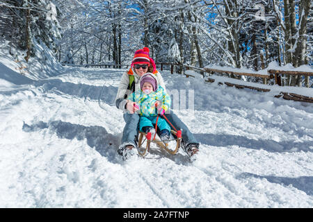 Mère et fille l'accélération en descente sur traîneau en bois. Banque D'Images