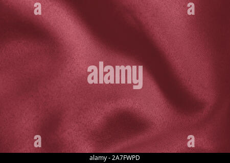 Arrière-plan de couleur rouge foncé de tissu drapé doux. Belle Soie satin tissu texturé pour la confection des vêtements et des rideaux. Texture textile élégant. Banque D'Images